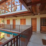 Charming villa exterior with wooden balcony and large windows showcasing natural views.