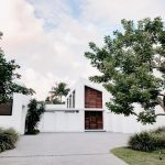 Contemporary minimalist home exterior with lush landscaping and open driveway.