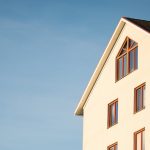 Minimalist modern residential building facade against clear blue sky.