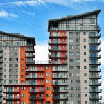 Modern high-rise apartment buildings with unique architecture under a vibrant blue sky.