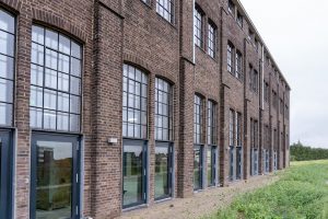 Side view of a historic brick building with large windows and modern renovation.